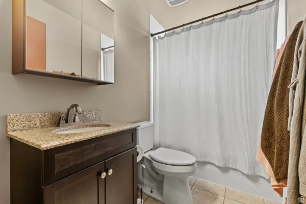 Bathroom with a dark wood-finish vanity, light-toned countertop, and tile flooring