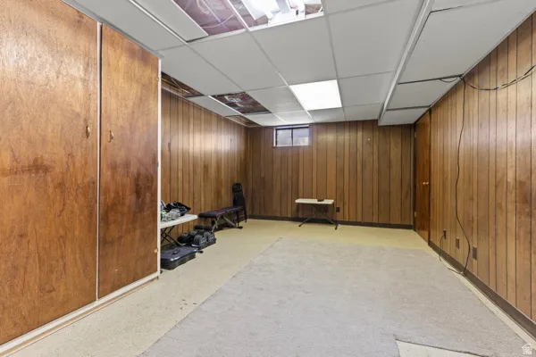 Wood-paneled room featuring drop ceiling, recessed lighting, and built-in wood-finish cabinetry
