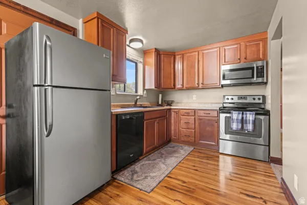 Full kitchen featuring wood-finish flooring, wood cabinetry, and stainless steel appliances