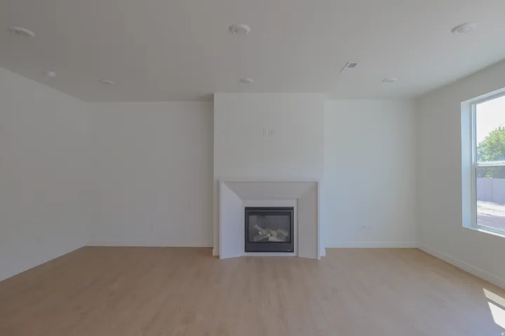 Recessed lighting, wood-finish flooring, built-in fireplace with a hearth, and a large window