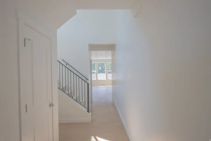 Entryway featuring light wood-finish flooring, white paneled door, and staircase with wrought iron railing