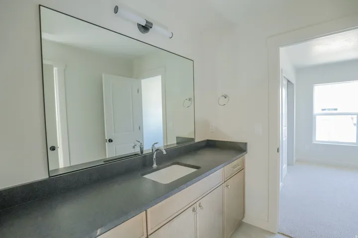 Vanity with integrated sink, sleek countertop, and extensive mirror