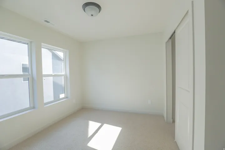 Neutral wall color, two windows, wall-to-wall carpeting, and a flush-mount ceiling light