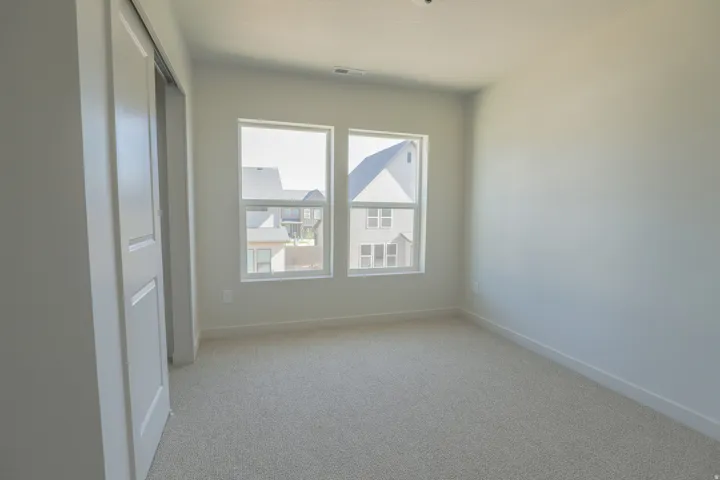 Neutral wall paint, two windows, and light-colored carpet
