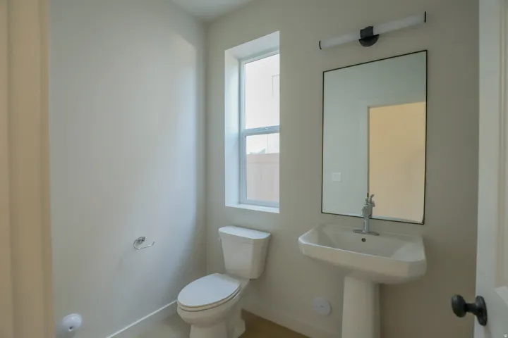 Pedestal sink with chrome faucet, framed mirror, and contemporary vanity lighting