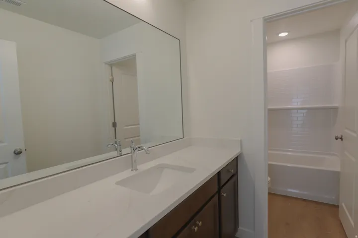 Long vanity with an integrated sink, polished chrome faucet, and expansive mirror