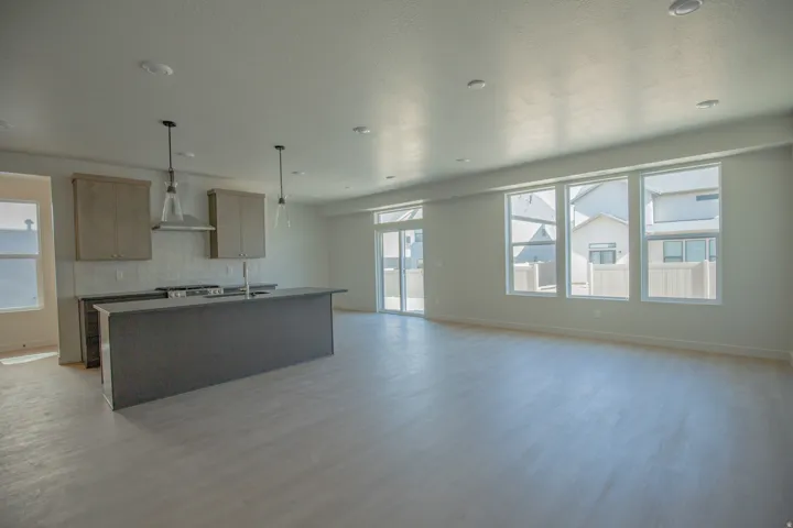 Open-concept living area with wood-finish flooring, recessed lighting, and large windows providing abundant natural light