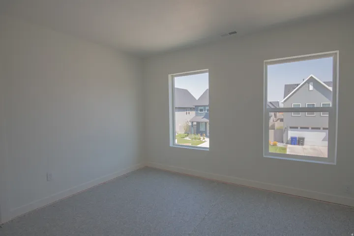 Neutral wall color, carpeted flooring, and two large windows