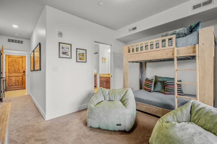 Integrated bunk bed structure with a ladder, carpeted flooring, white walls, and a wood-paneled door