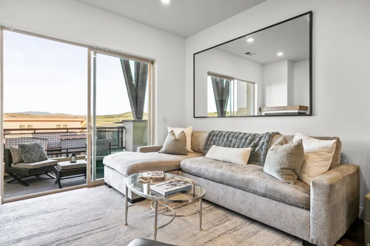Recessed lighting, sliding glass door leading to an outdoor balcony, white walls, and a large wall-mounted mirror with a black frame