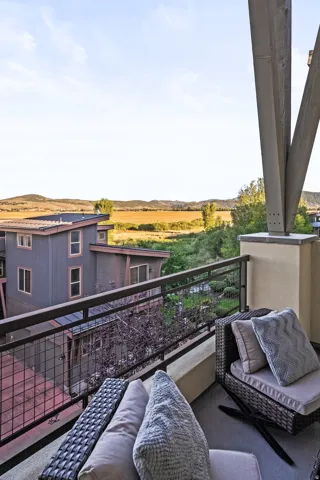 Balcony with metal railing, concrete flooring, and distant field scenery