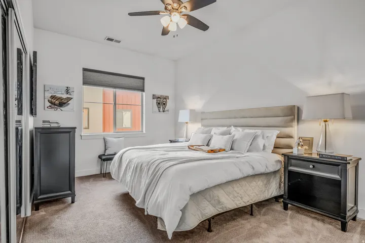 Bedroom featuring a ceiling fan with integrated lighting, a window with blinds, and carpet flooring