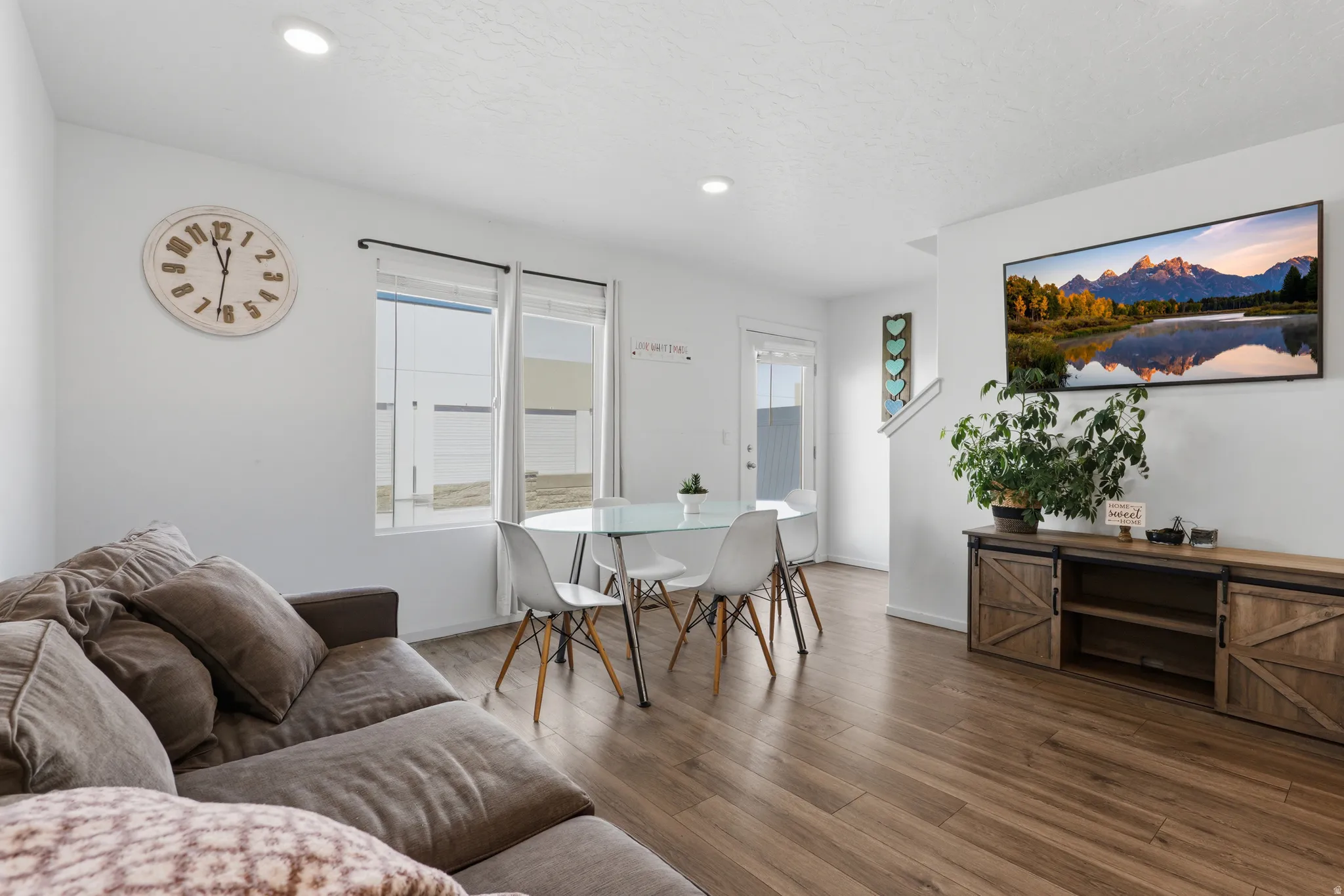 Open-concept living area with wood-finish flooring, recessed lighting, and a dining space