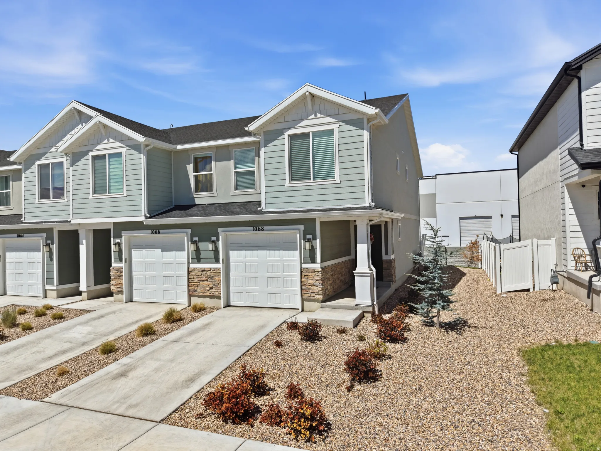 Contemporary townhome exterior featuring light blue siding, white trim, and stone accents
