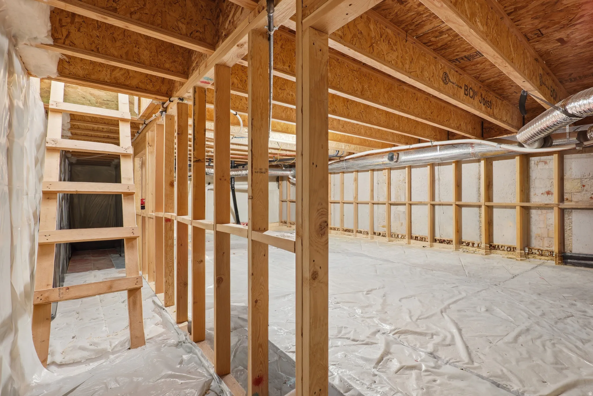 Unfinished basement with exposed wood framing, wood subfloor, and ceiling joists