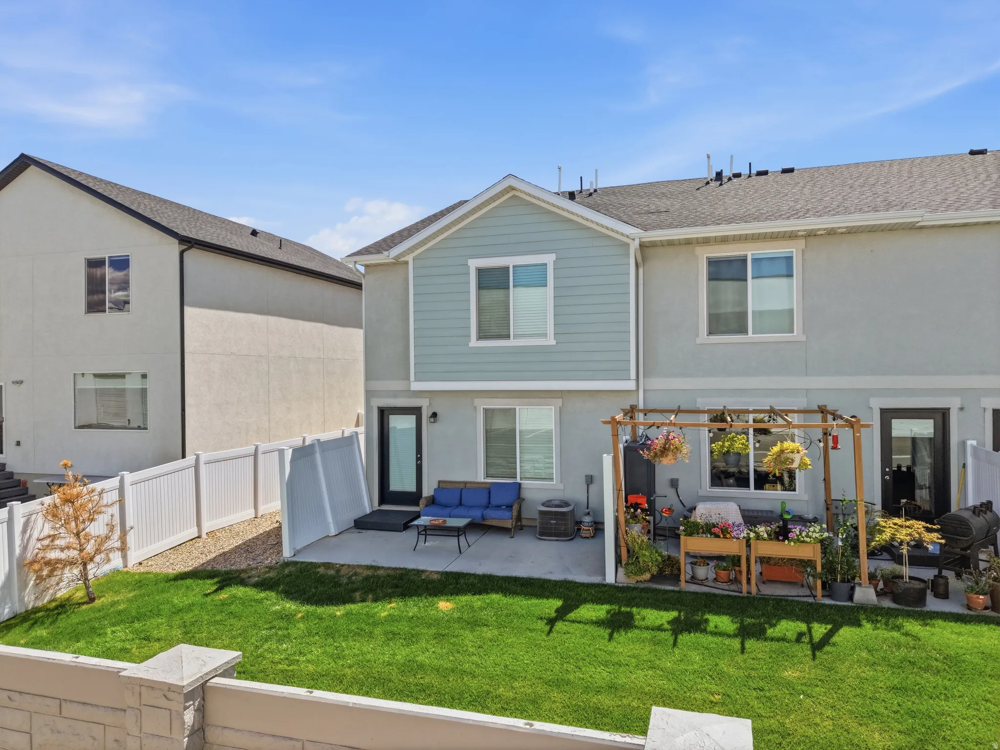 Expansive lawn area, concrete patio, white privacy fencing, and wood pergola structure