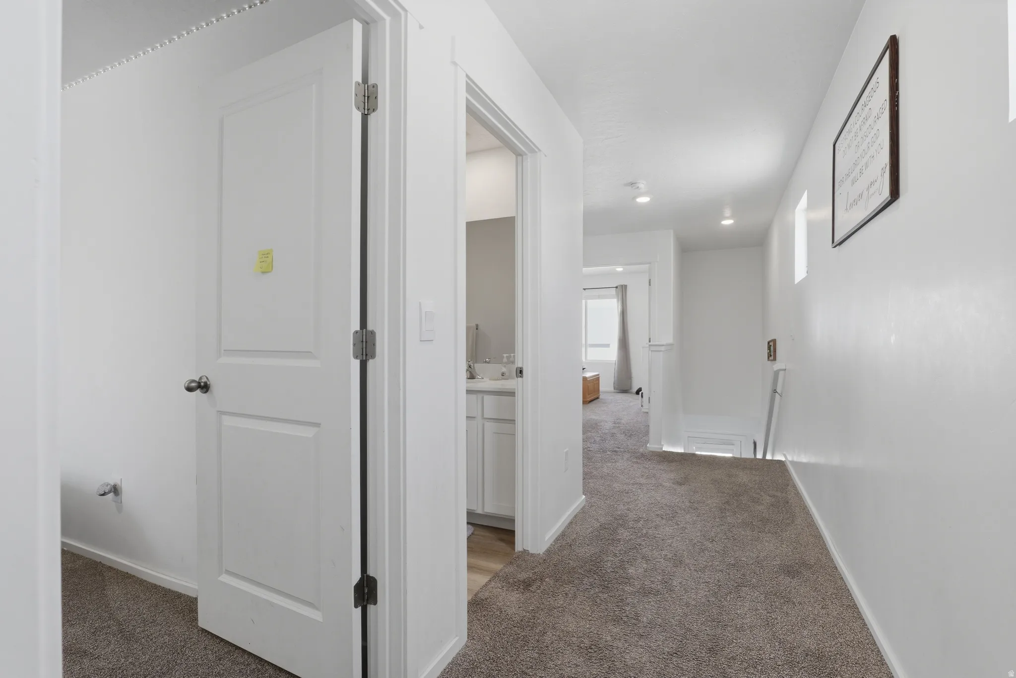 Plush carpeted hallway with recessed lighting and a paneled interior door