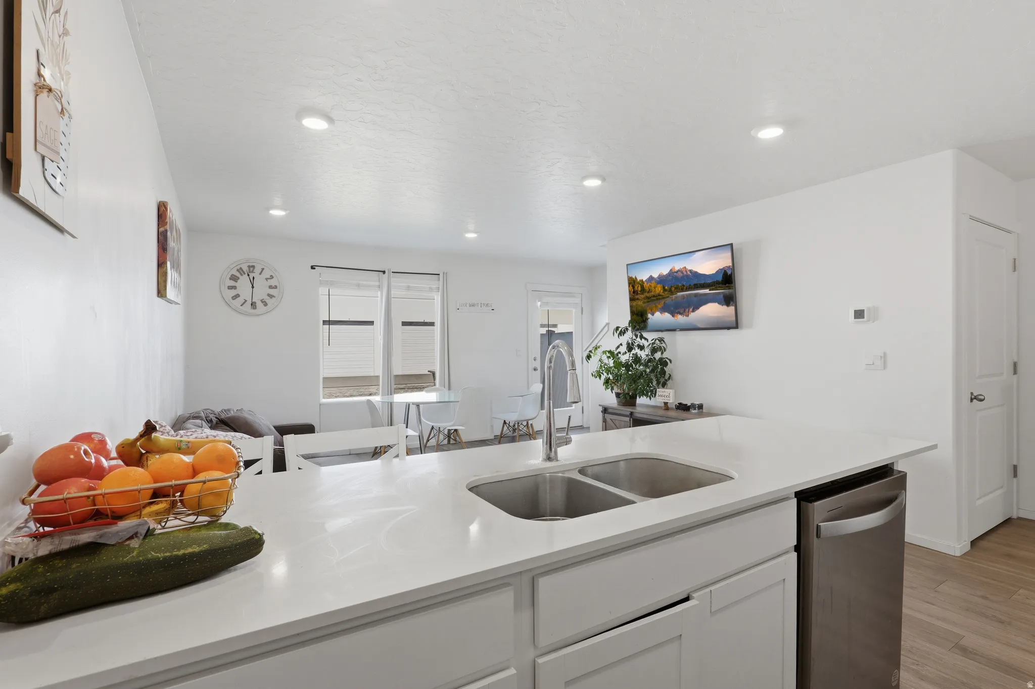 Kitchen island with a double basin sink, white countertops, and a stainless steel dishwasher