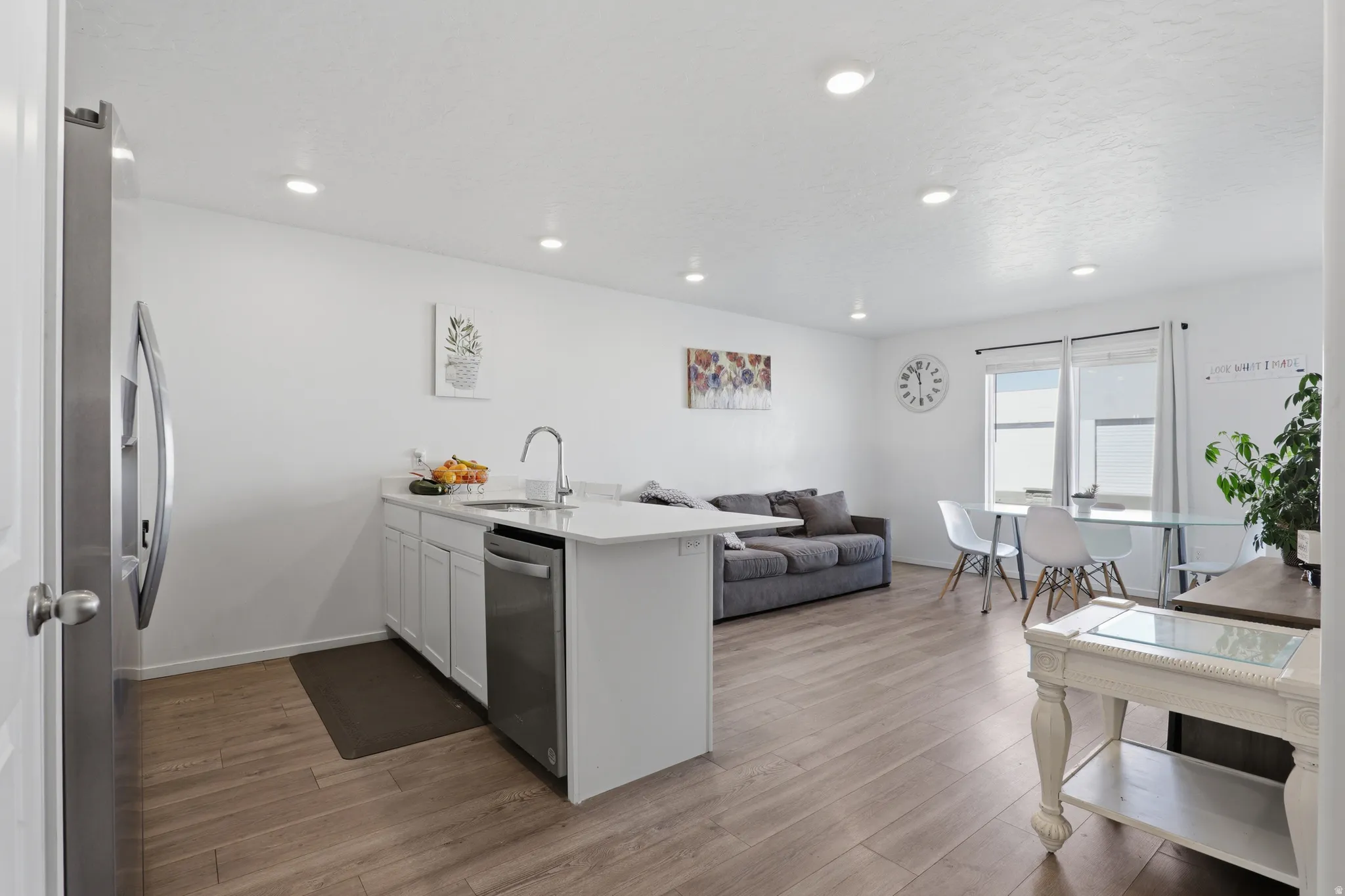 Open-concept living space with wood-finish flooring, recessed lighting, and white walls