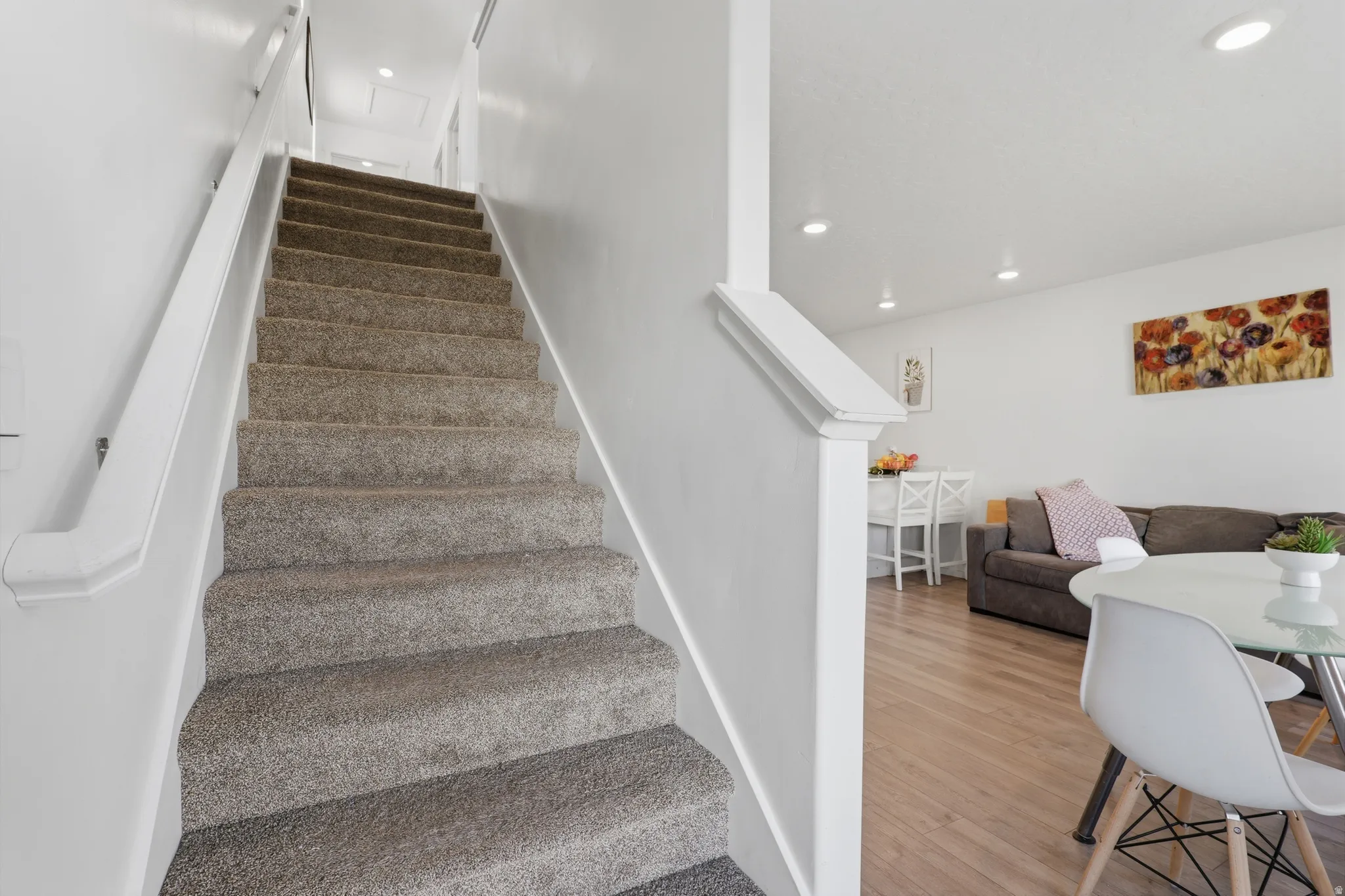 Carpeted staircase with white handrail and solid wall