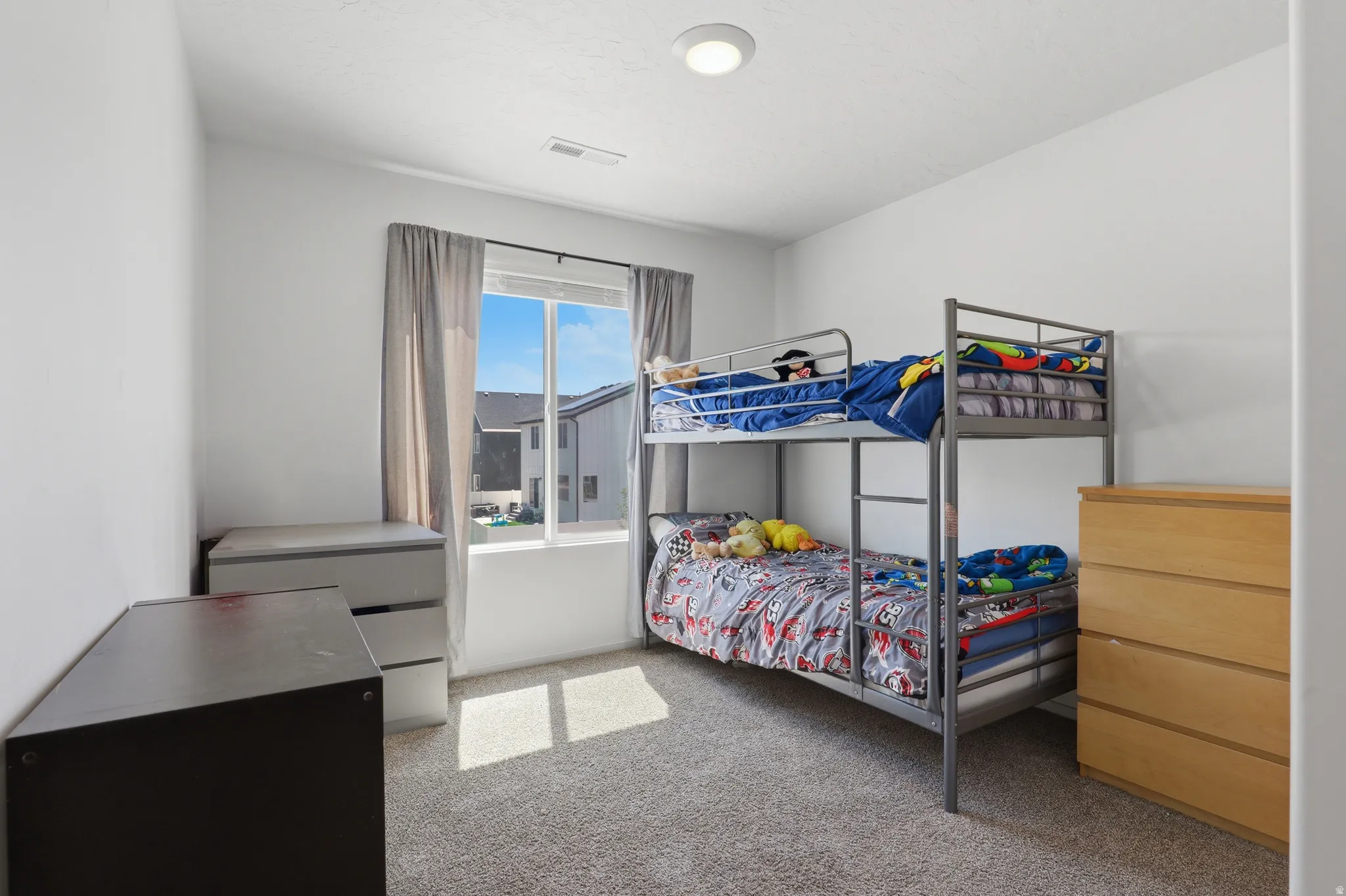 Carpeted flooring, white walls, flush mount ceiling light, and a window with curtains