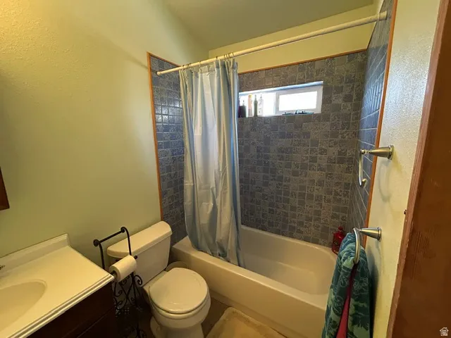 Bathtub with tiled surround, transom window, and vanity with integrated sink