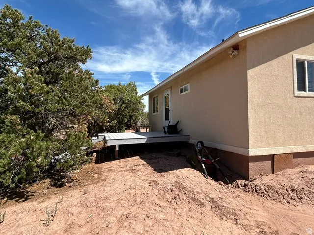 Stucco exterior with a raised composite deck, multiple windows, and exterior lighting fixture