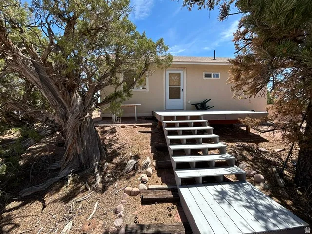 Exterior featuring a neutral stucco finish, white trim windows, and a white deck with steps