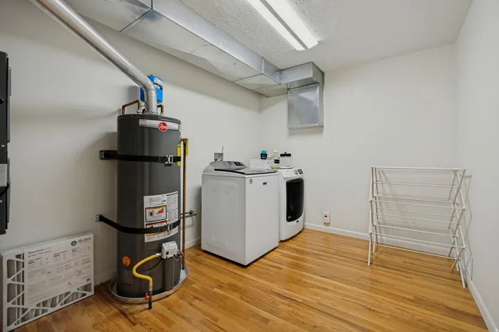 Utility space featuring wood-finish flooring, white walls, and exposed ductwork