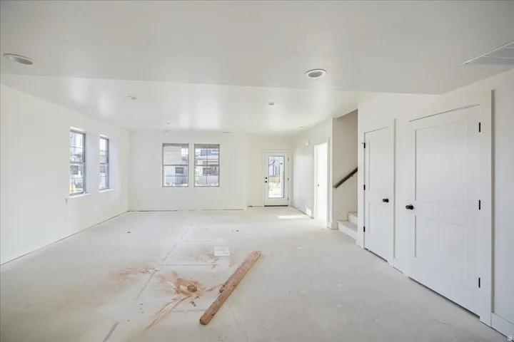 Spacious room with multiple windows, recessed lighting, and white paneled doors with matte black hardware