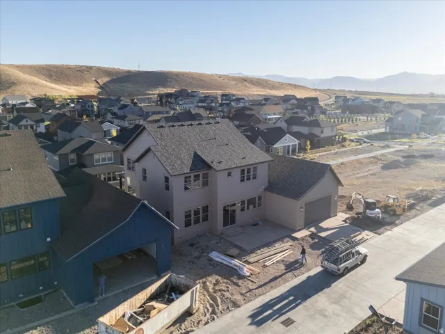 Contemporary two-story residence with attached garage, concrete patio, and a shingle roof