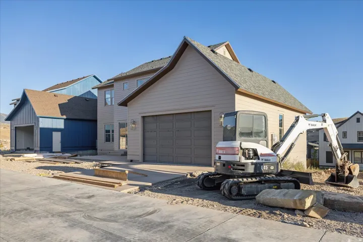 Attached two-car garage with a paneled door, light-colored siding exterior, and a gabled roofline