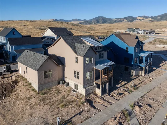 Multi-story residence featuring light-toned siding, a stone foundation, and a covered balcony
