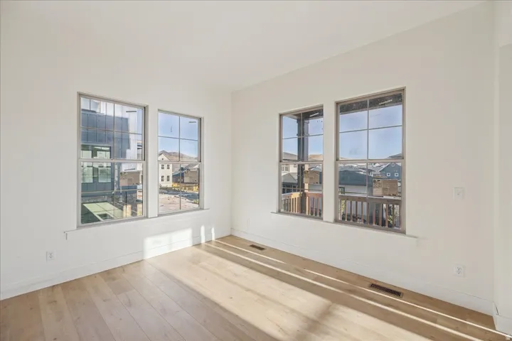 Light wood-finish flooring, white painted walls, and multiple windows with grid detailing