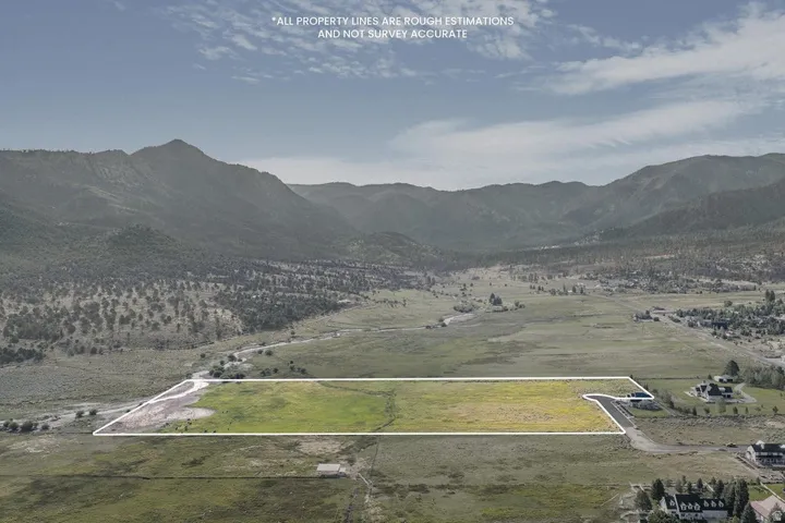 Expansive land parcel with surrounding mountain scenery and adjacent natural water feature