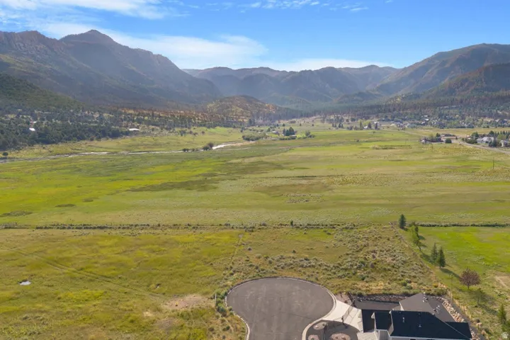 Expansive green field with surrounding mountain range and partial cul-de-sac