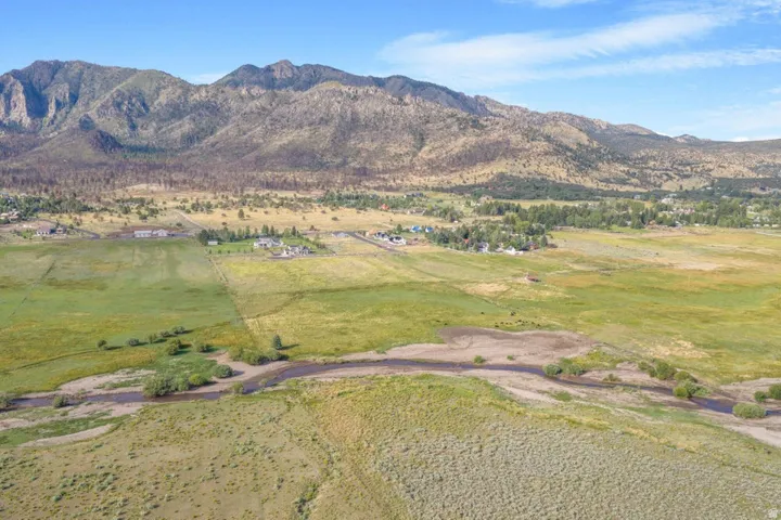 Expansive land parcel featuring open fields, a meandering waterway, and distant mountain backdrops