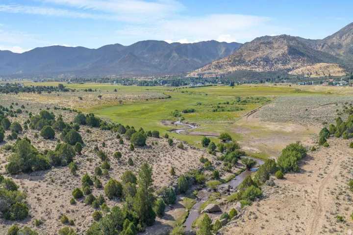 Mountainous backdrop with a winding river and expansive green pastures