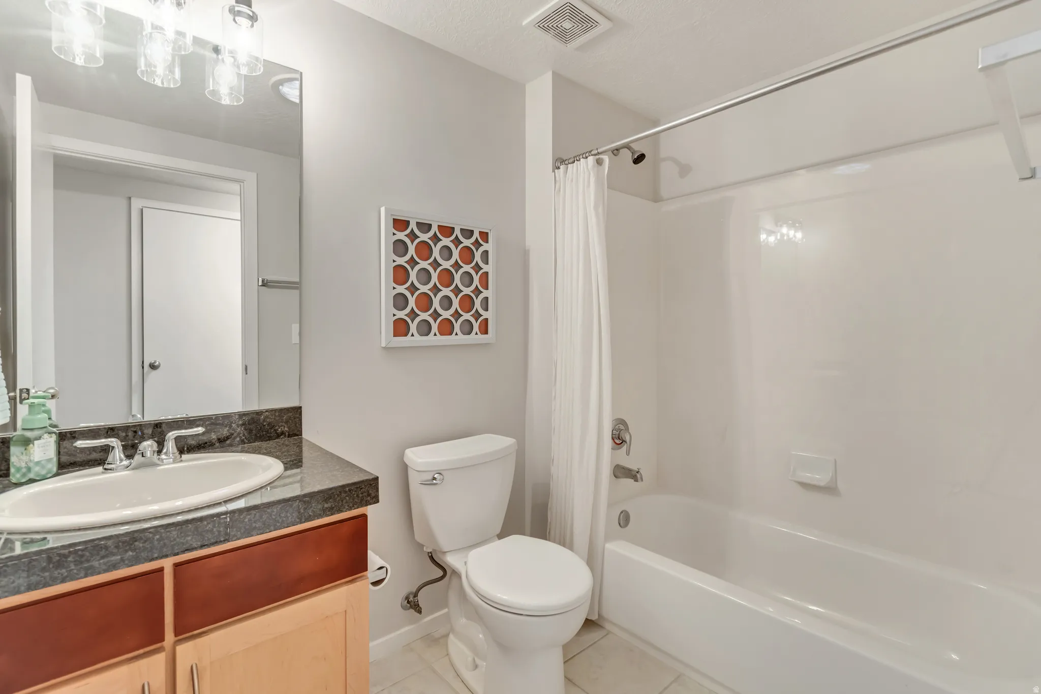 Vanity with undermount sink, dark stone countertop, and wood-finish cabinetry