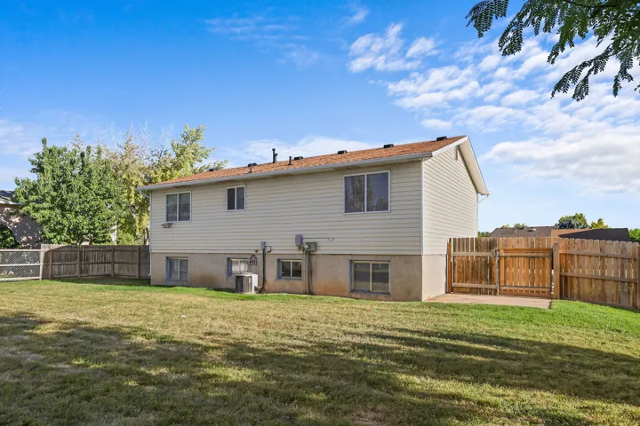 Expansive backyard with a manicured lawn, full privacy fencing, and a concrete patio