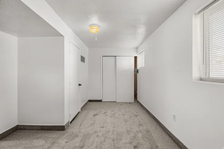 Spacious hallway with neutral wall finishes, carpeted flooring, and abundant natural light from a side window