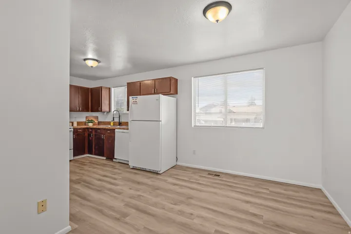 Wood-finish flooring throughout, white walls, and a large window with blinds