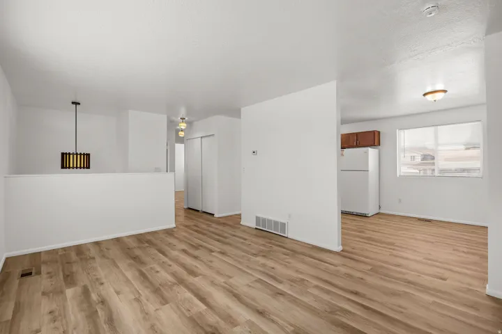 Wood-finish flooring throughout, white walls, and a contemporary pendant light fixture