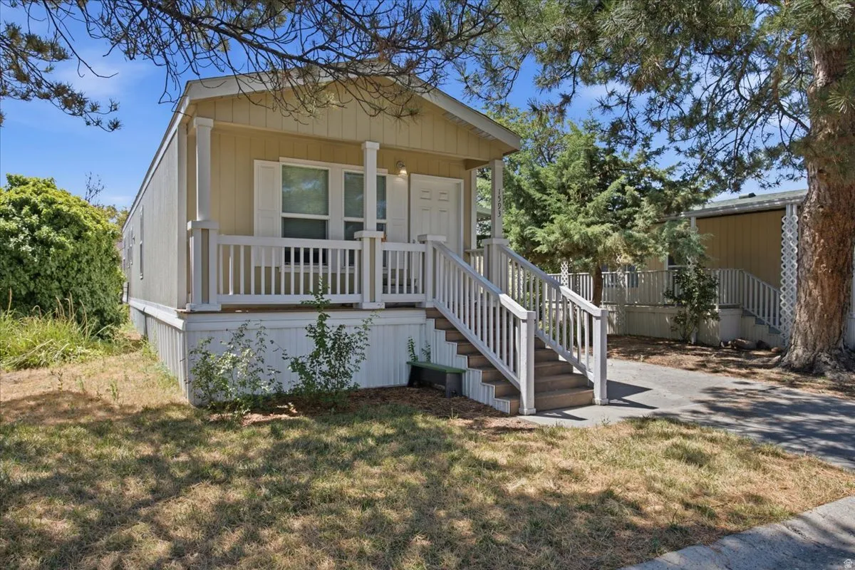 Exterior featuring a covered porch, white railing, and a multi-level staircase