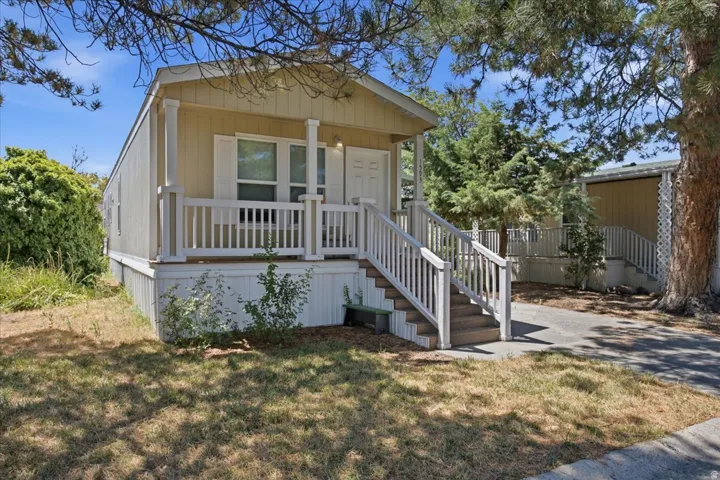 Exterior featuring a covered porch, white railing, and a multi-level staircase