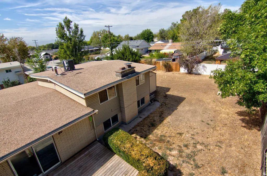 Brick and siding exterior, expansive backyard, wood deck, mature trees, and a flat roof