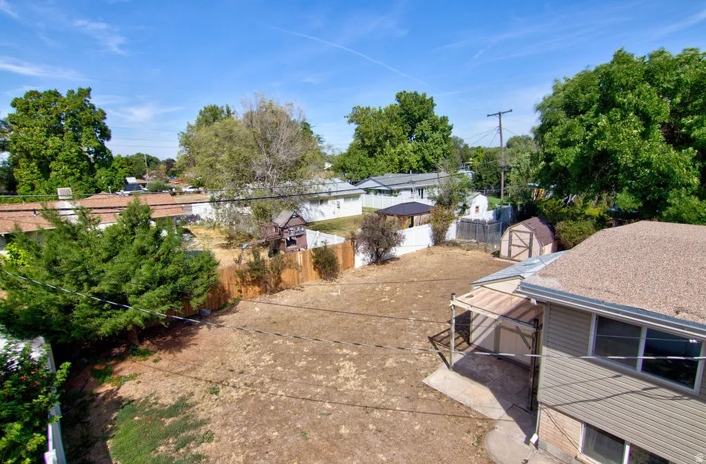Expansive backyard with a storage shed, covered patio, and a privacy fence