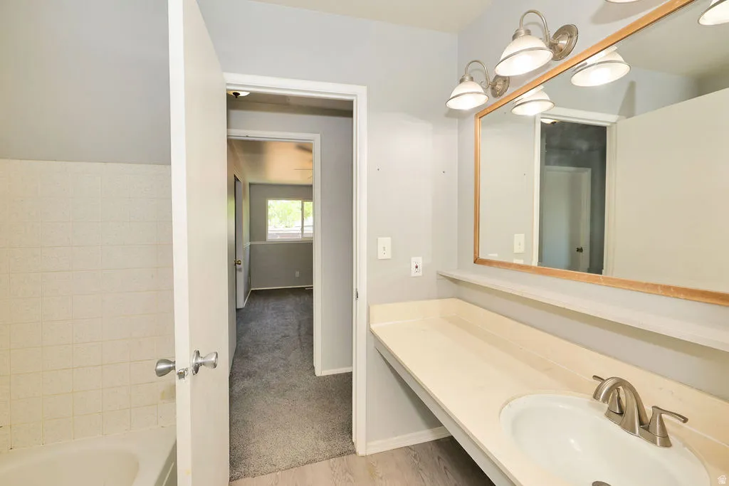 Vanity with integrated sink, brushed nickel faucet, large mirror with wood-finish frame, and overhead lighting