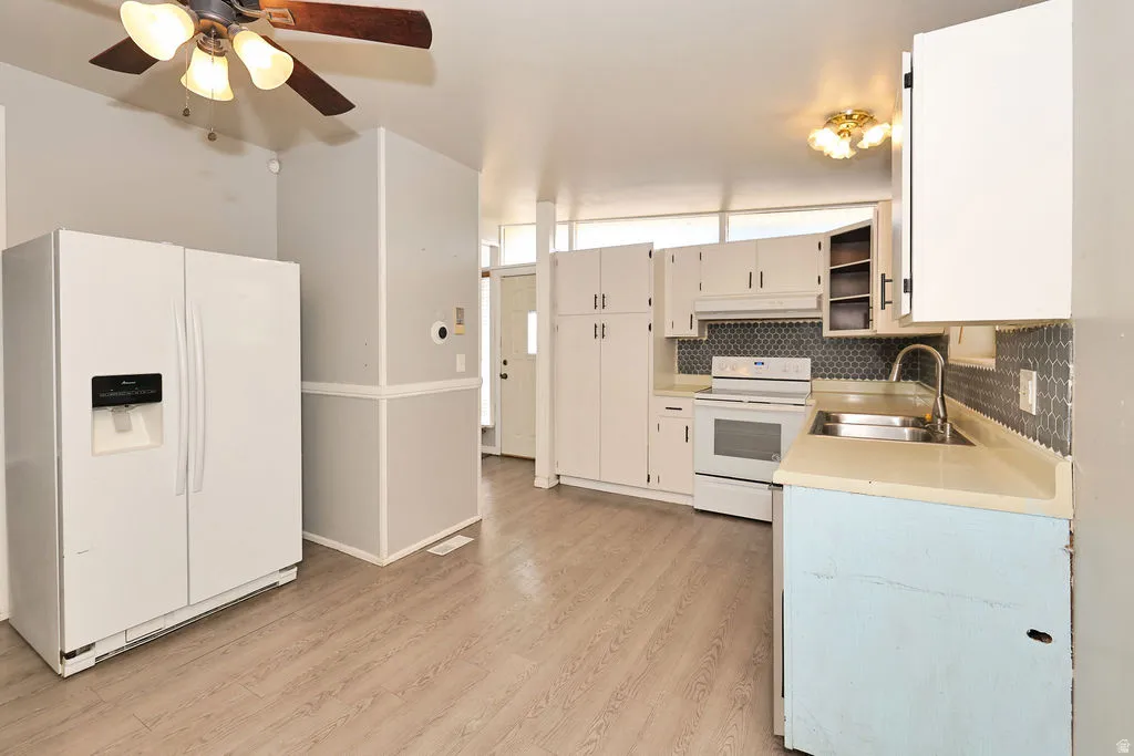 Wood-finish flooring, white cabinetry, integrated stainless steel sink, tiled backsplash, and ceiling fan
