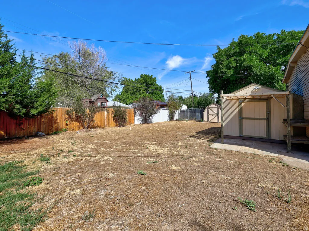 Expansive backyard featuring a wood fence, storage shed, and a secondary storage shed